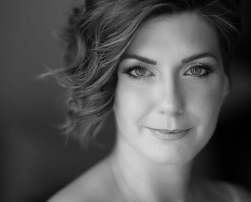 Κλασικό ασπρόμαυρο κοντινό πορτραίτο γυναίκας που κοιτάζει τον φακό με ένα απαλό χαμόγελο.