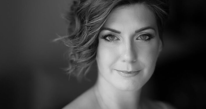 Κλασικό ασπρόμαυρο κοντινό πορτραίτο γυναίκας που κοιτάζει τον φακό με ένα απαλό χαμόγελο.