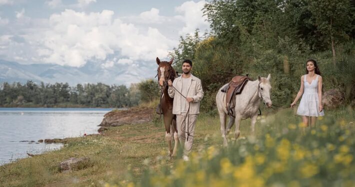 Το νιόπαντρο ζευγάρι περπατάει στη φύση μαζί με δύο άλογα κατά τη διάρκεια της φωτογράφισης μετά τον γάμο.