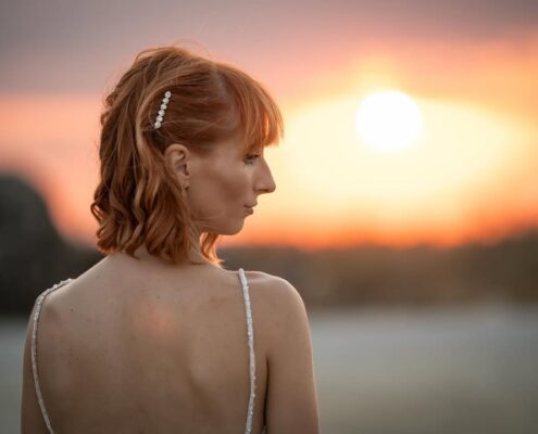 Εντυπωσιακό πορτραίτο της νύφης που κοιτάζει στο πλάι με φόντο το ηλιοβασίλεμα.