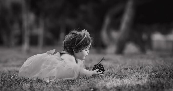 Ασπρόμαυρη καλλιτεχνική φωτογραφία μικρού παιδιού που παίζει στο γρασίδι.