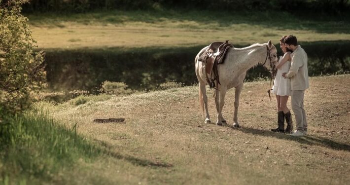 Φωτογράφιση του ζευγαριού μετά τον γάμο σε καταπράσινο τοπίο με ένα λευκό άλογο.