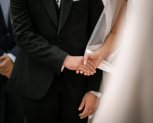 Κοντινή φωτογραφία με τα ενωμένα χέρια του γαμπρού και της νύφης.