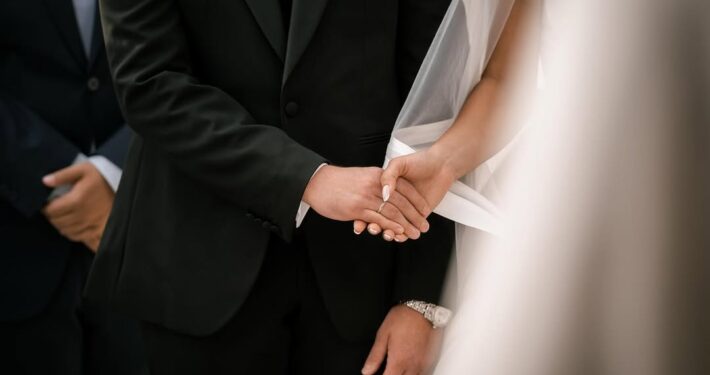 Κοντινή φωτογραφία με τα ενωμένα χέρια του γαμπρού και της νύφης.