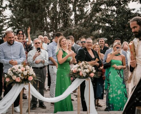 Οι καλεσμένοι του γάμου παρακολουθούν και χειροκροτούν κατά τη διάρκεια της υπαίθριας τελετής.