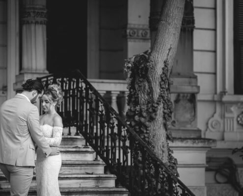 Το ζευγάρι στέκεται δίπλα σε πέτρινα σκαλιά σε μια ατμοσφαιρική ασπρόμαυρη λήψη.