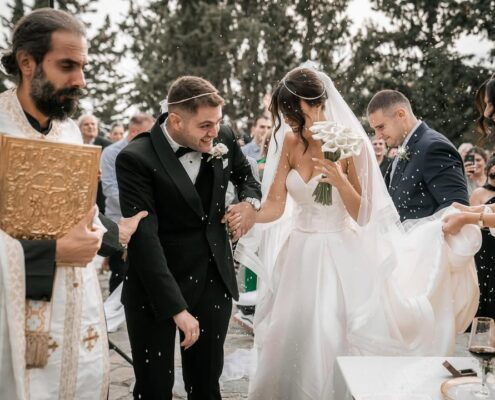 Ο γαμπρός φιλάει το χέρι της νύφης κατά τη διάρκεια της γαμήλιας τελετής σε εξωτερικό χώρο.