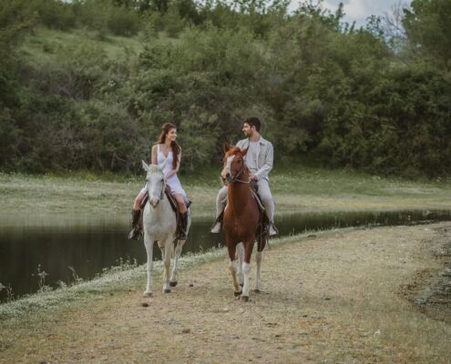 Νιόπαντρο ζευγάρι κάνει βόλτα με άλογα στο δάσος σε μια next day φωτογράφιση.