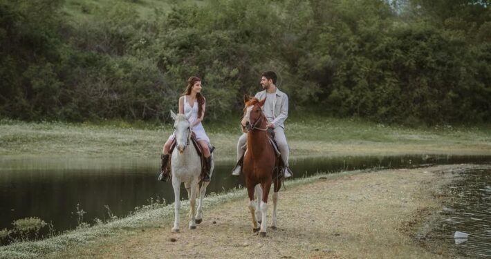 Νιόπαντρο ζευγάρι κάνει βόλτα με άλογα στο δάσος σε μια next day φωτογράφιση.