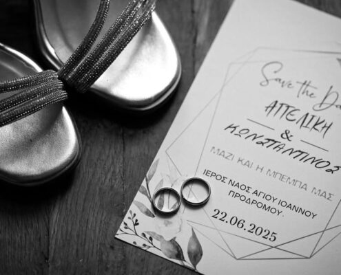 Ασπρόμαυρη flatlay φωτογραφία με τα προσκλητήρια του γάμου, τις βέρες και τα παπούτσια.