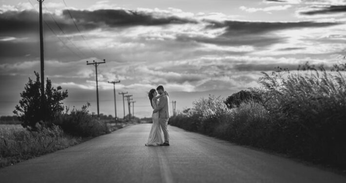 Ευρυγώνια ασπρόμαυρη λήψη ζευγαριού σε εξοχή κάτω από συννεφιασμένο ουρανό.